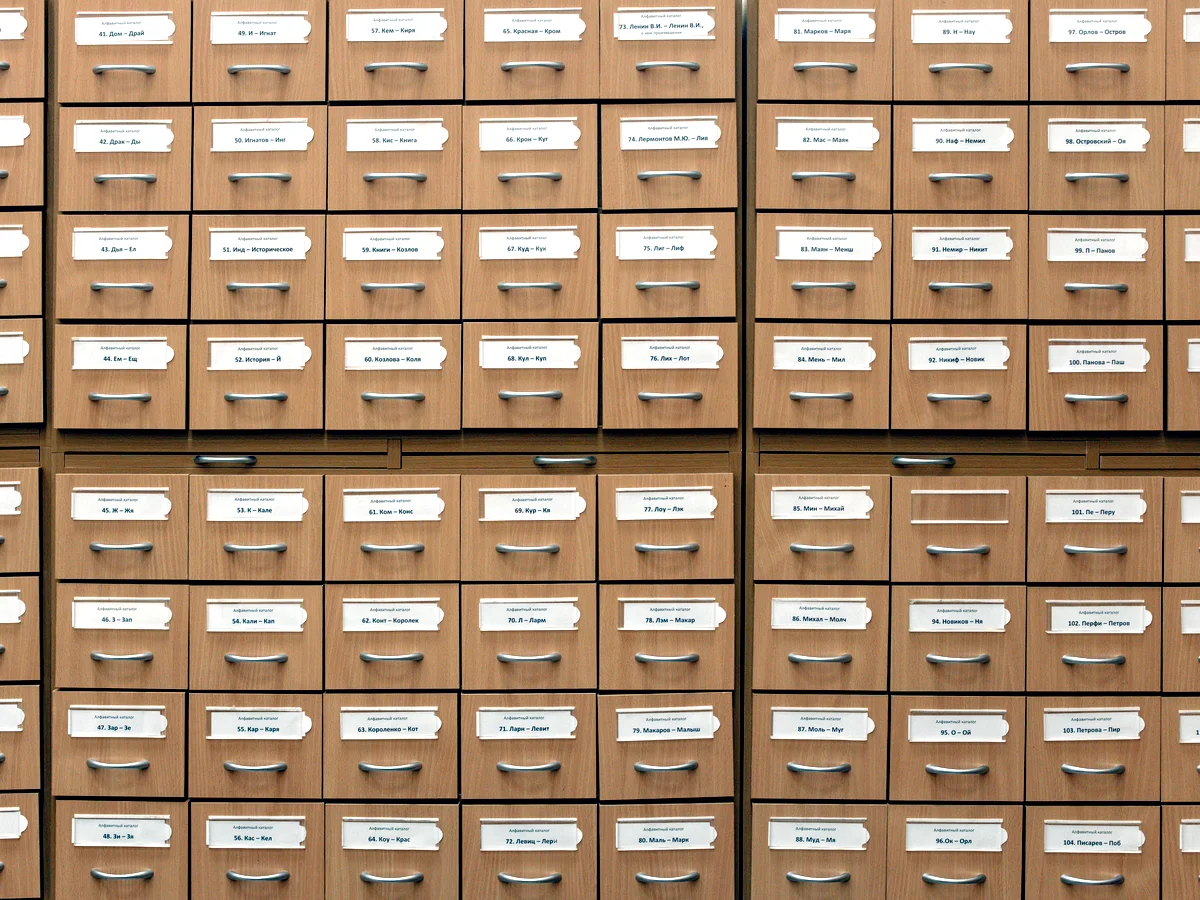A wall of shallow labelled drawers holding the exhibition records.